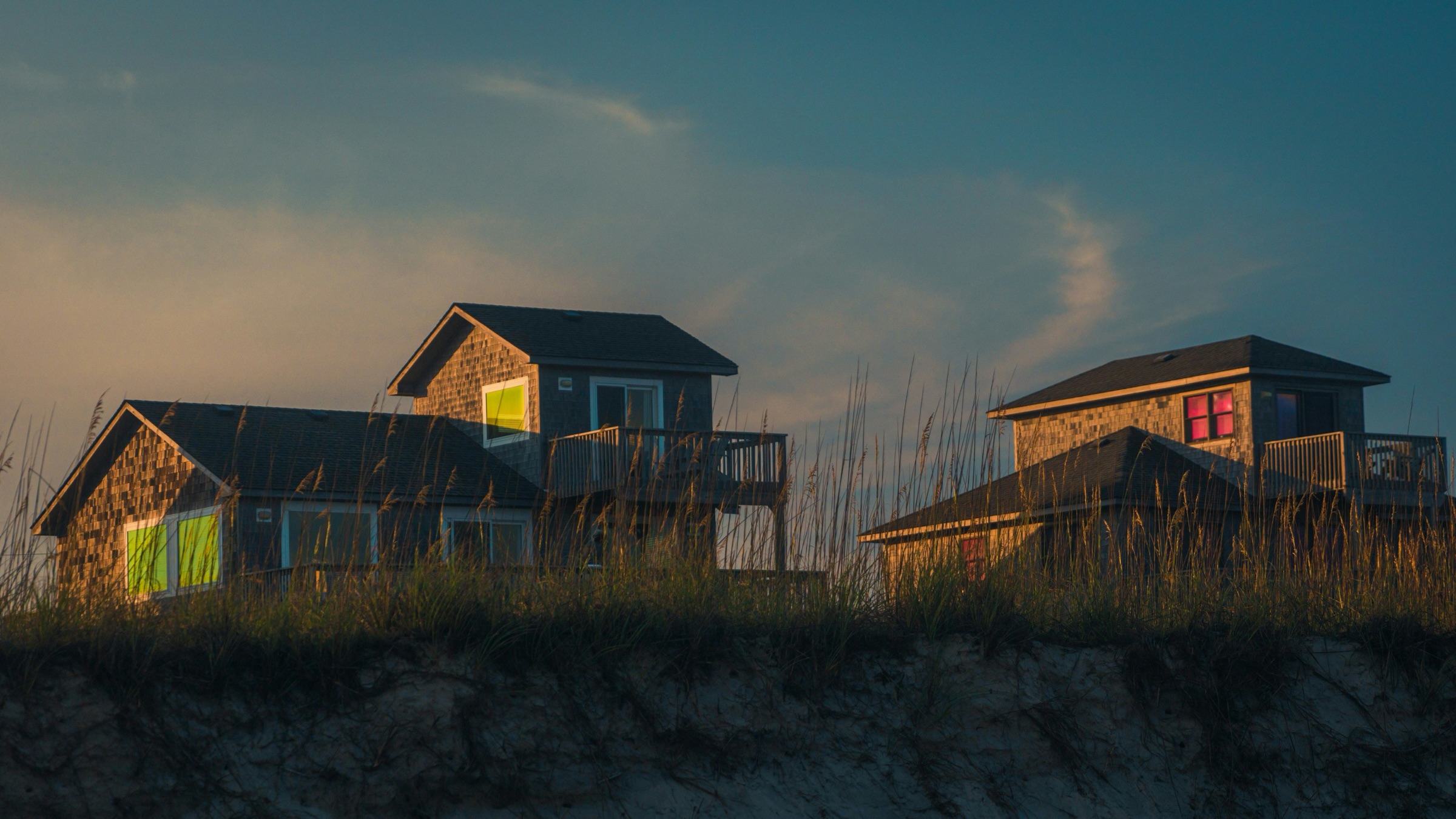 Beach houses at dusk with warmly lit windows